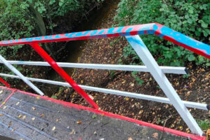 Zniszczone niebieskim sprayem barierki mostku w Marcyporębie